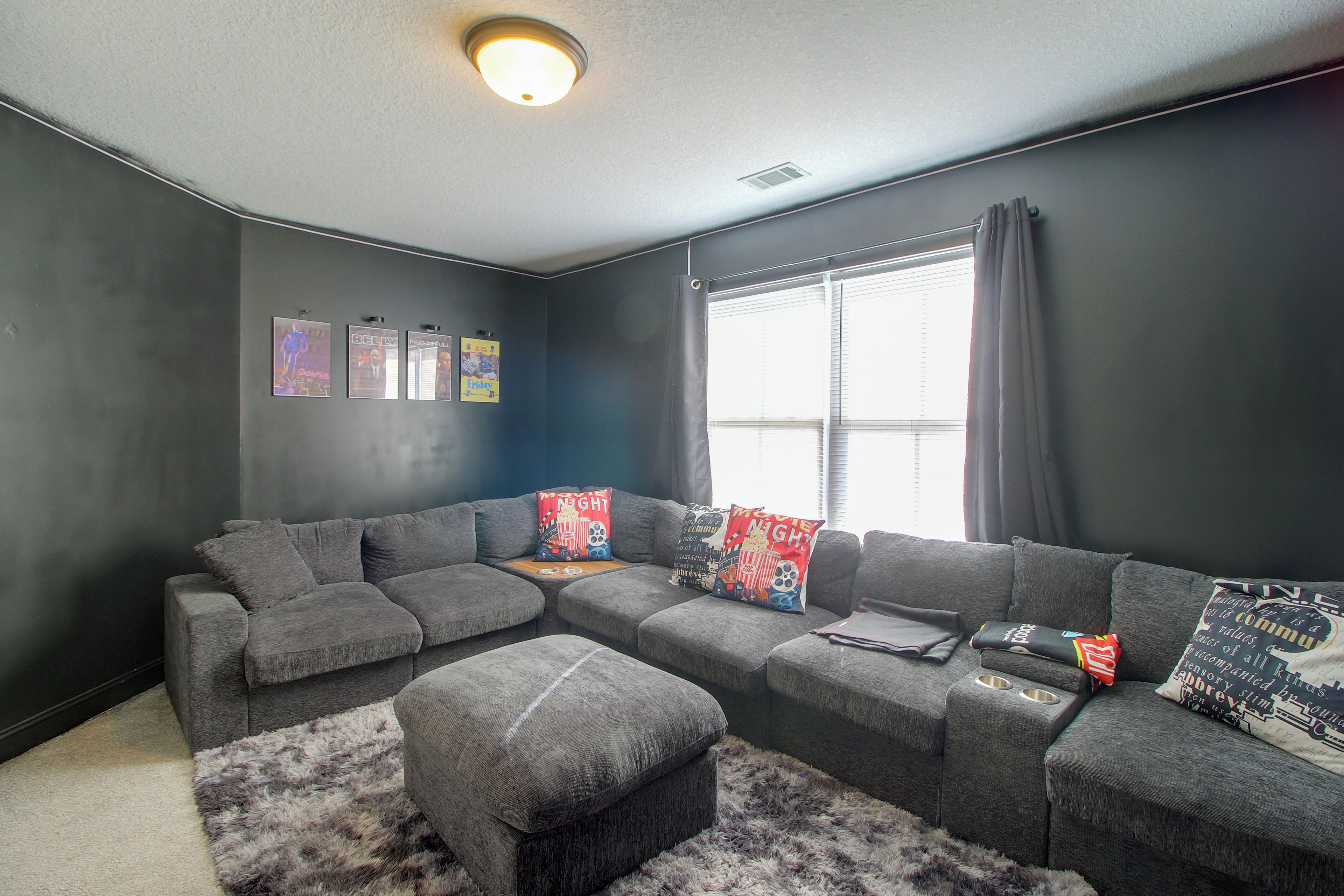 A modern living room with a sectional sofa, a small ottoman, and a fluffy rug.