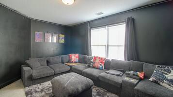 A modern living room with a sectional sofa, a small ottoman, and a fluffy rug.