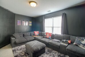A modern living room with a sectional sofa, a small ottoman, and a fluffy rug.