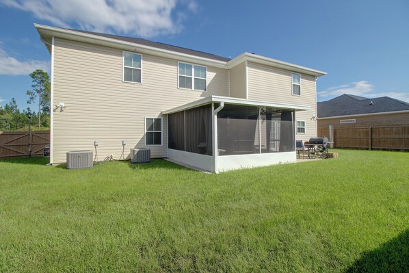 A two-story house with a covered patio area, a fenced yard, and an air conditioning unit.