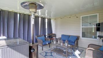 Un patio couvert aménagé avec des meubles en osier, une table et un radiateur.