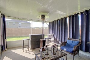 A covered patio area with wicker furniture, a table, and a heater.
