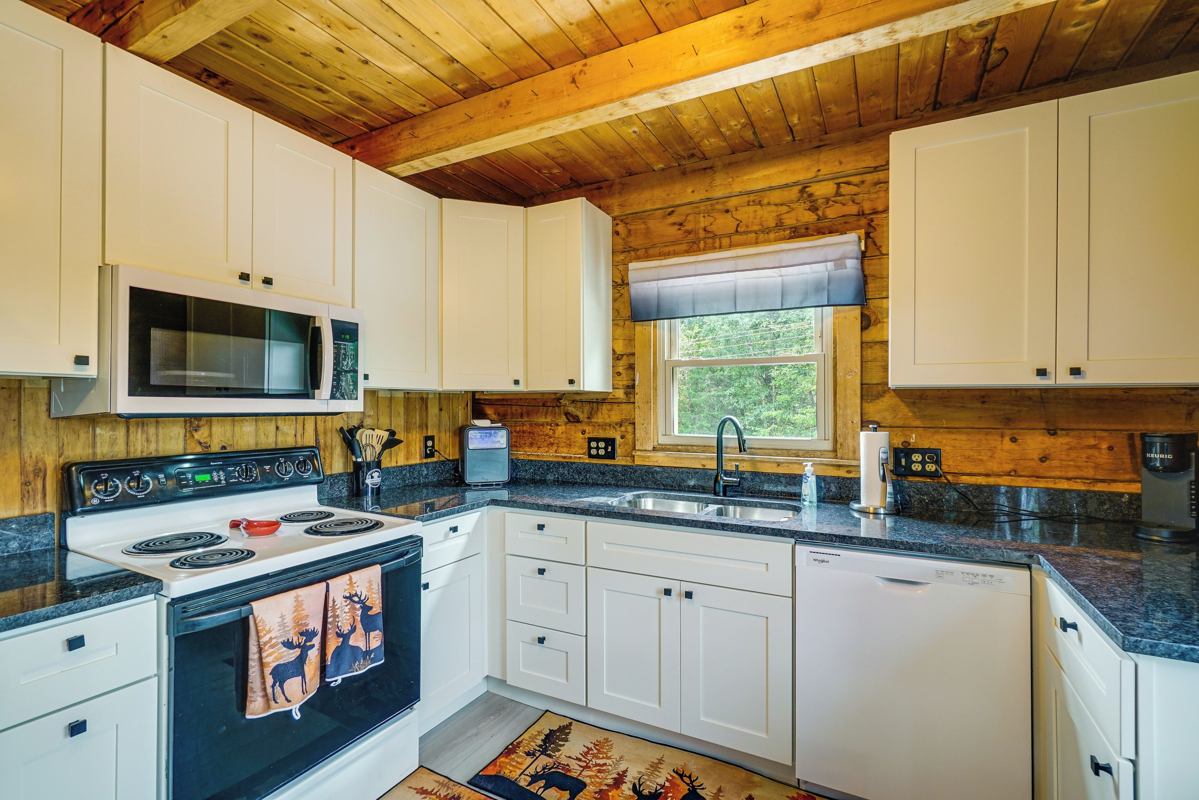 A kitchen with white cabinets, a microwave, a stove, and a sink.