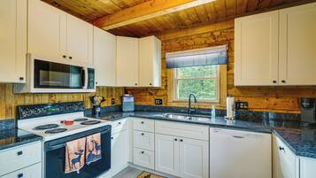 A kitchen with white cabinets, a microwave, a stove, and a sink.