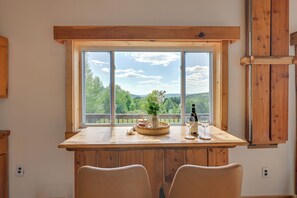 A wooden dining table with two chairs, a vase with flowers, and a wine glass.