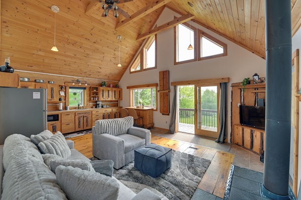 A spacious living area with a high ceiling, wooden beams, and large windows.