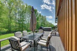 An outdoor deck with a table and chairs, a grill, and a view of the surrounding greenery. - Hot Tub & Amazing Views! Family Catskills Cabin (Hobart)