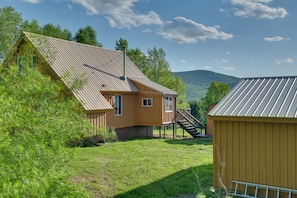 A wooden cabin with a sloped roof, a small porch, and a staircase leading to a deck.