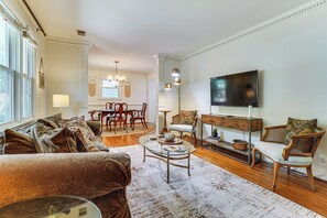 Ein Wohnzimmer mit einer Couch, einem Couchtisch, einem Fernseher und einem Essbereich mit Stühlen und einem Tisch.