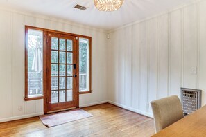Ein Zimmer mit Holztür, weißen Wandverkleidungen, Holzboden und einer Deckenleuchte.