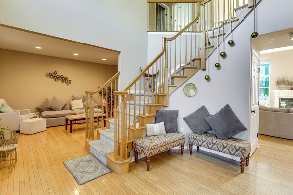 A spacious living area with a wooden staircase, a sofa set, and a dining table.