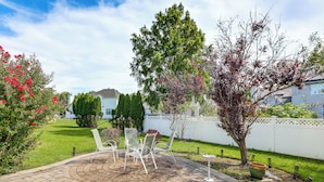 A patio area with a brick floor, white chairs, and a white fence in the background. - Spacious Group Getaway Near Grounds For Sculpture (Hightstown)