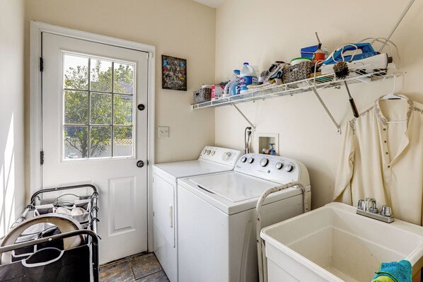 A laundry area with a washer and dryer, a drying rack, and a shelf with cleaning supplies.