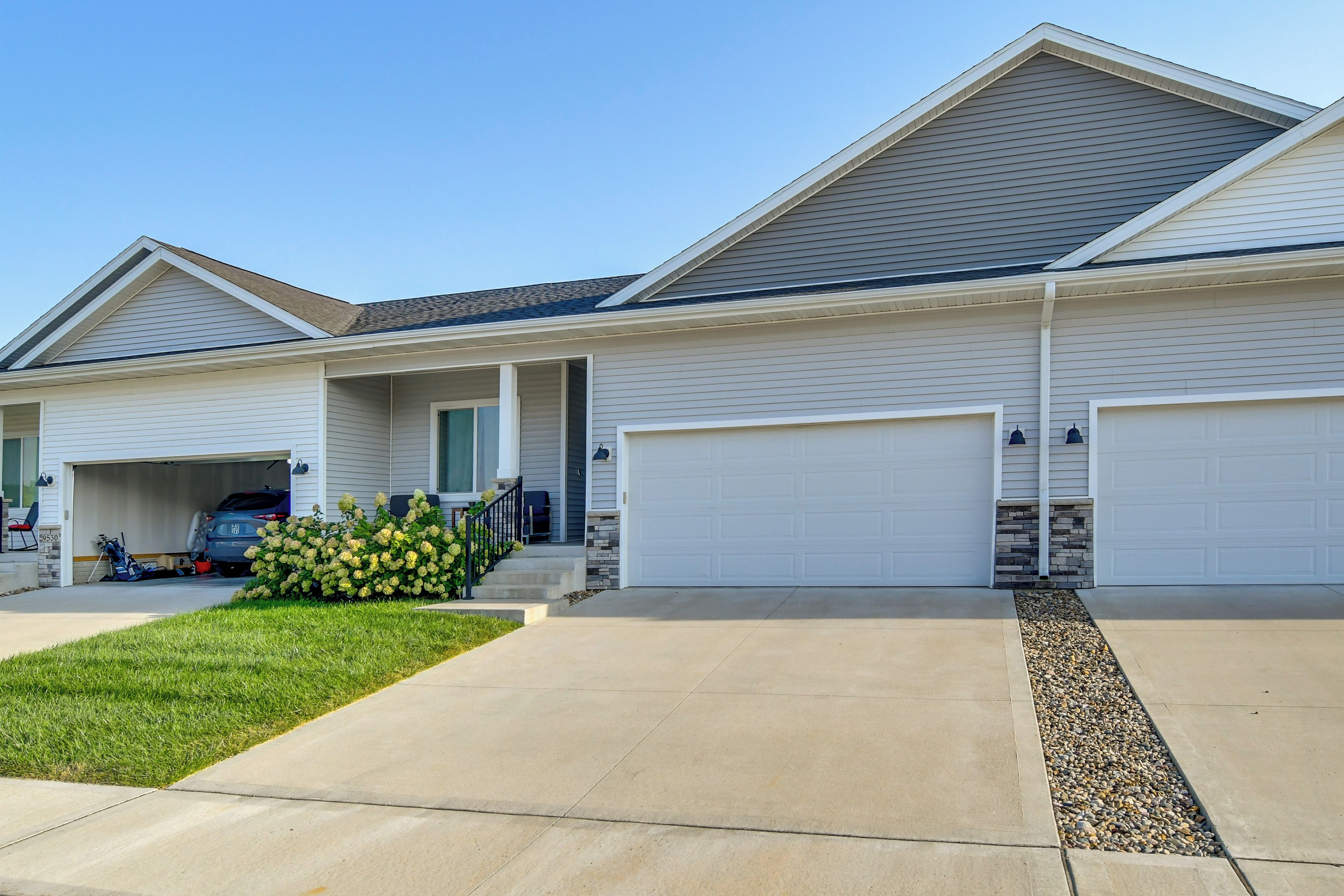 A two-story residential building with a garage, a covered porch, and a well-maintained lawn.
