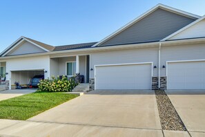 A two-story residential building with a garage, a covered porch, and a well-maintained lawn.