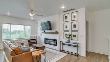 A modern living room with a sofa, coffee table, fireplace, and wall-mounted TV.