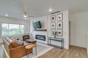A modern living room with a sofa, coffee table, fireplace, and wall-mounted TV.