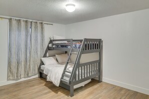 A bunk bed with a ladder, a window with curtains, and a ceiling light.
