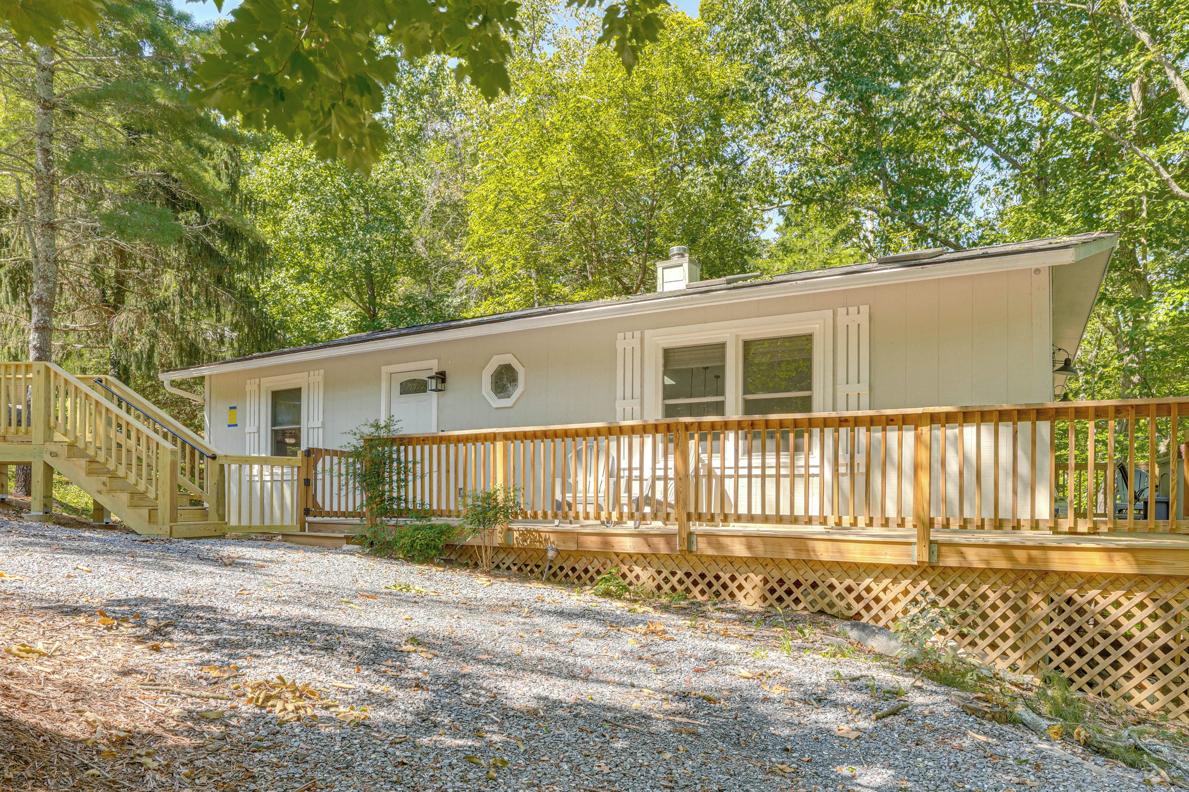 A single-story house with a wooden deck and a gravel driveway.