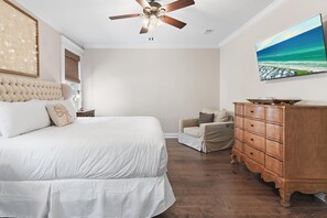 A bedroom with a large bed, a wooden dresser, a chair, and a ceiling fan. - Vitamin Sea- VCB (Destin)