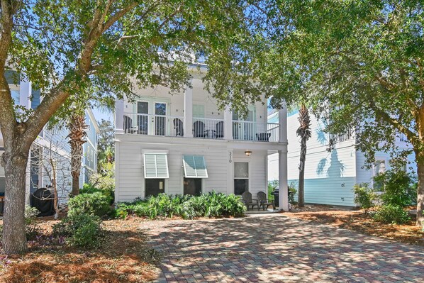 A two-story building with a balcony, a paved driveway, and a view of the water. - Vitamin Sea- VCB (Destin)