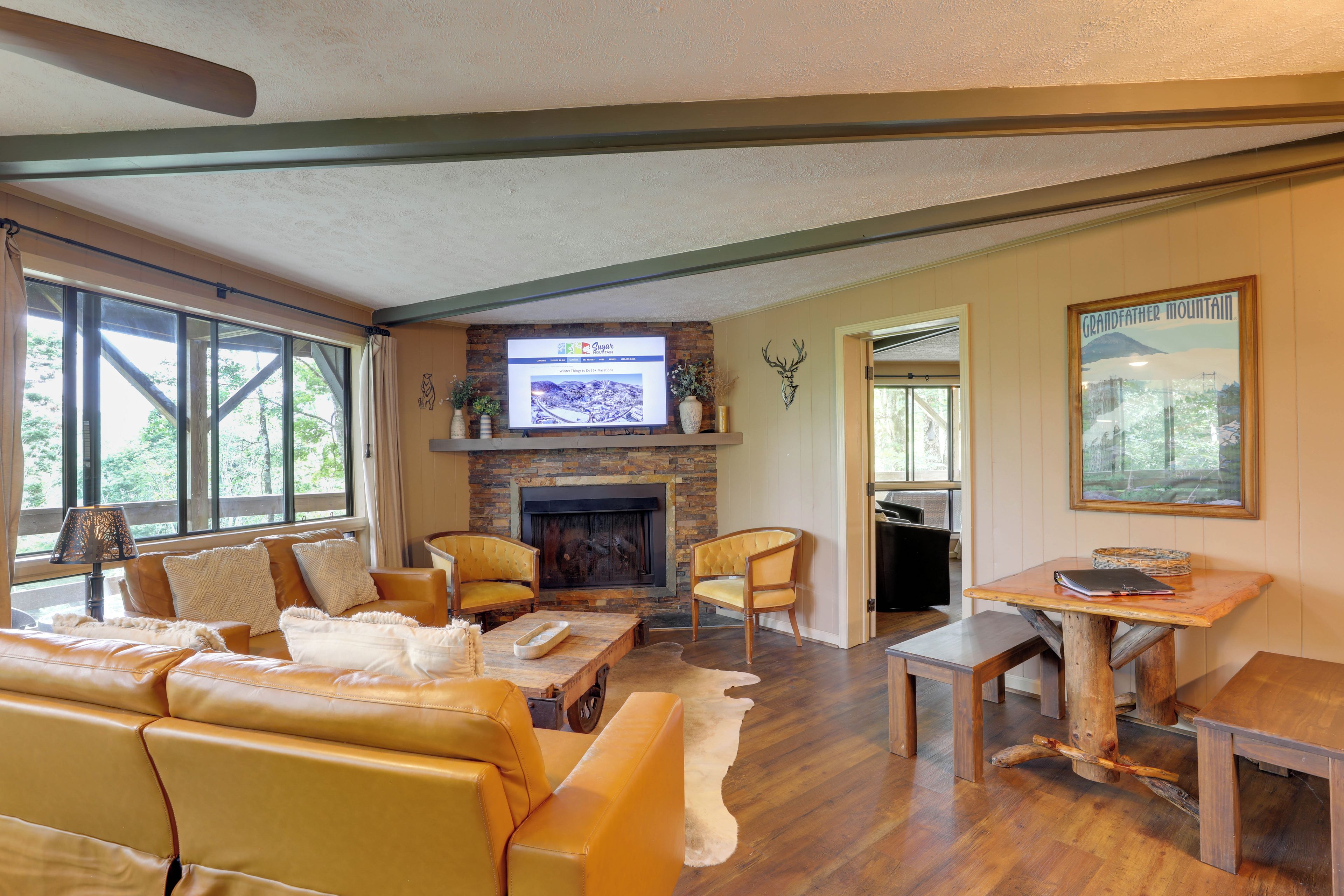 A cozy living room with a fireplace, leather sofa, and a television mounted above it.