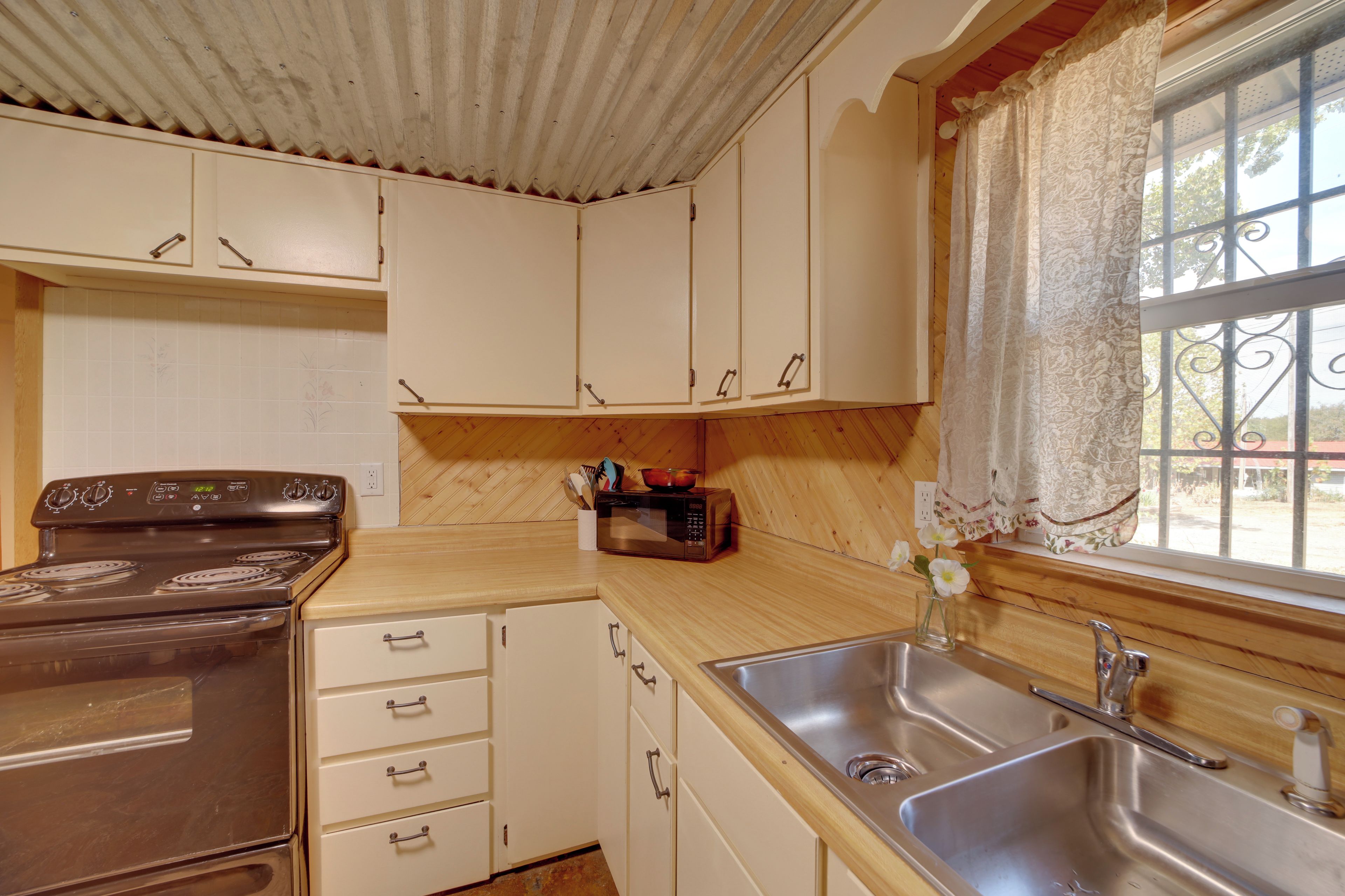 Una cocina con estufa, microondas, pileta y alacenas.