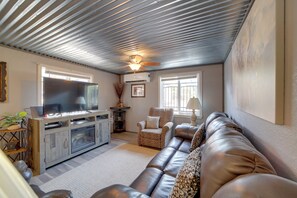 Ein Wohnzimmer mit Flachbildfernseher, Kamin, Sofa und Deckenventilator.