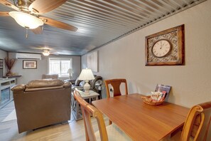 Ein Wohnzimmer mit einer Ledersofa, einem Holzesstisch, einer Wanduhr und einem gerahmten Bild.