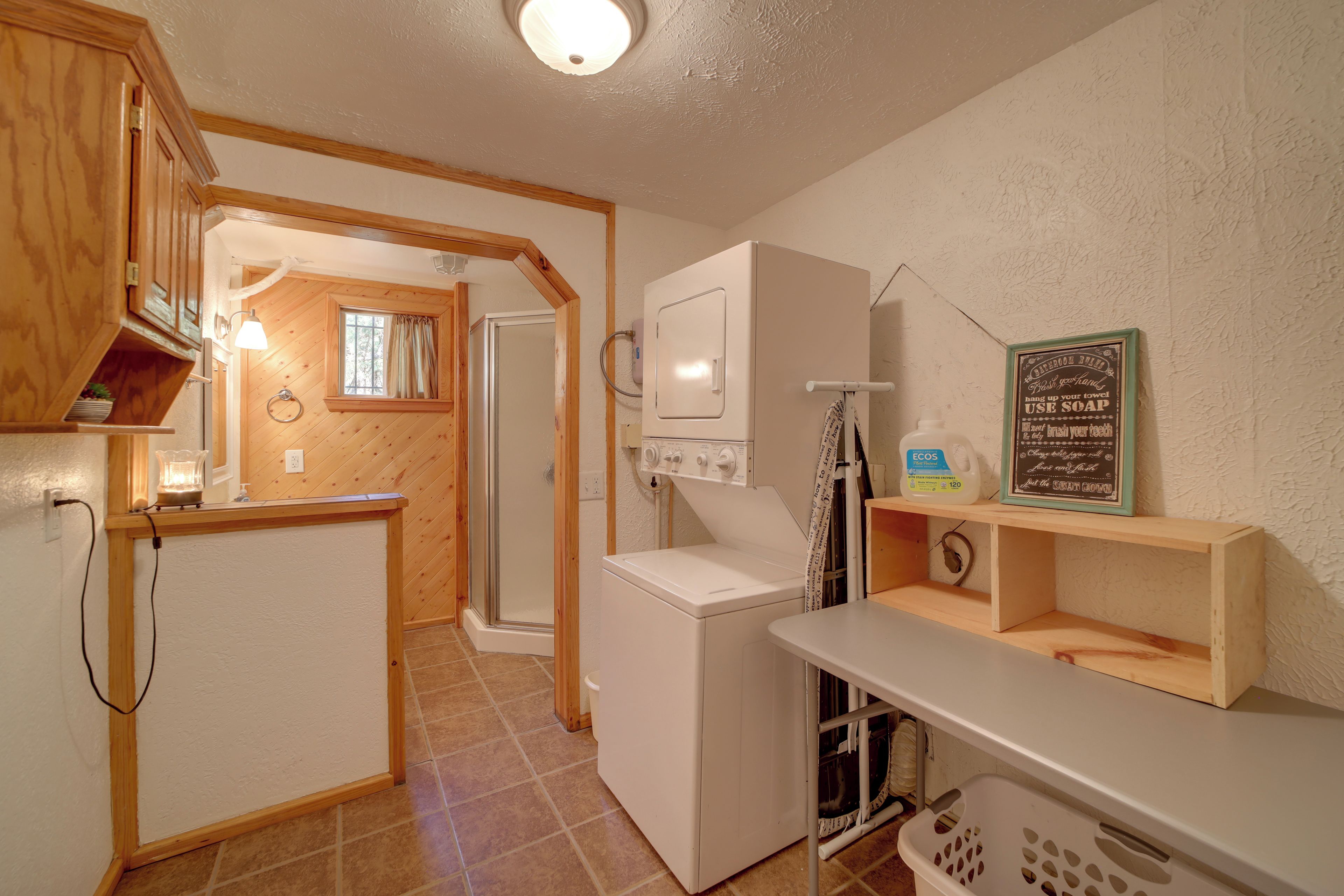 A compact kitchen with a washing machine, a small sink, and a window with curtains.