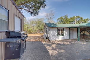 Área residencial com casa, telhado verde, garagem e churrasqueira ao primeiro plano.