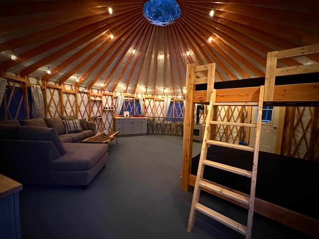 L’intérieur d’une yourte, avec un canapé, une échelle et un motif circulaire au plafond.