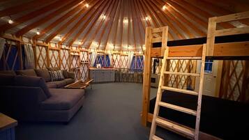 A yurt interior with a sofa, a ladder, and a circular ceiling design.