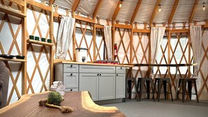 A cozy interior with a wooden table, a small plant, and a kitchen area with stools.