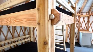 A wooden bunk bed with a black mattress, a wooden headboard, and a ladder.