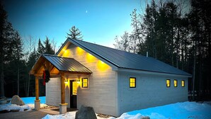 A cabin with a porch, a door, and windows.