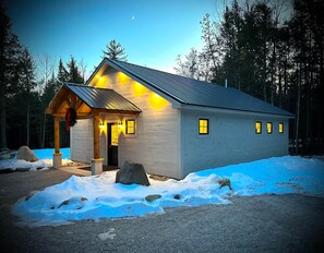 A cabin with a porch, a door, and windows.