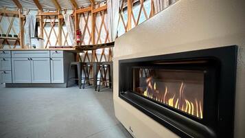 A modern kitchen with a built-in fireplace, wooden beams, and a white countertop.