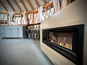 Eine moderne Küche mit eingebautem Kamin, Holzbalken und einer weißen Arbeitsplatte.