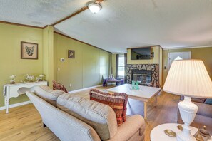 Uma sala de estar com lareira, mesa de jantar e um conjunto de sofás.