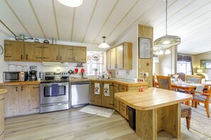 A kitchen with wooden cabinets, stainless steel appliances, and a wooden dining table.
