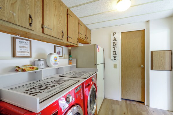 A laundry room with wooden cabinets, a washing machine, a refrigerator, and a wall-mounted sign.