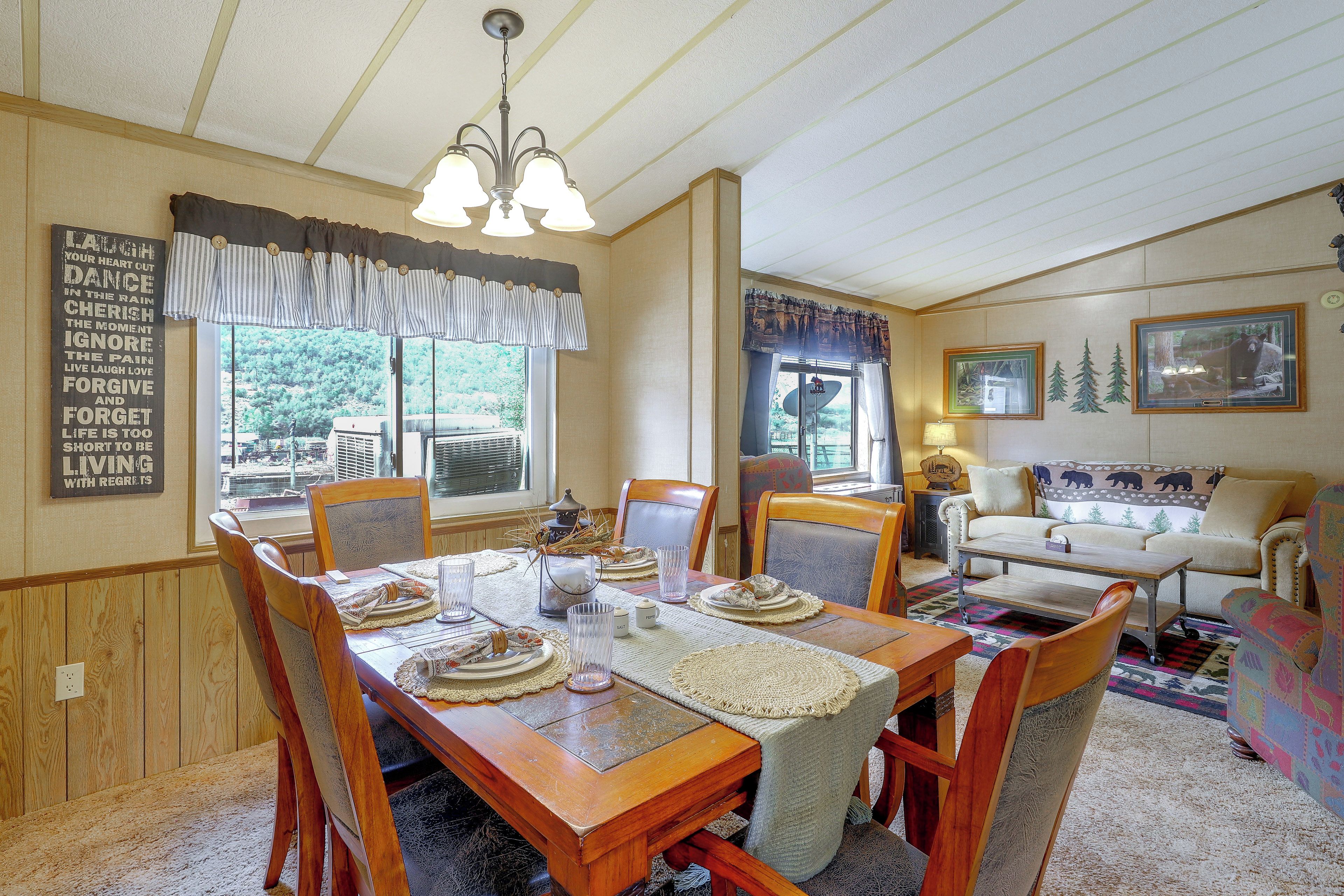 A dining room with a wooden table set for four, surrounded by chairs.