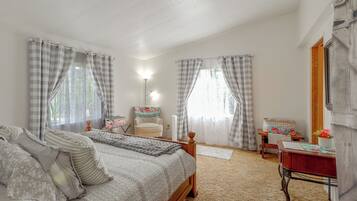 A bedroom with a bed, a chair, a desk, and a mirror.