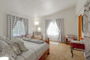 A bedroom with a bed, a chair, a desk, and a mirror.