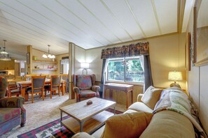 A cozy living room with a dining area, a patterned armchair, and a view through the window.