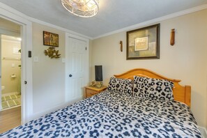 A bedroom with a bed, a nightstand, a wall-mounted lamp, and a door. - Walk to Tuskegee University! Apt w/ Shared Yard (Tuskegee)