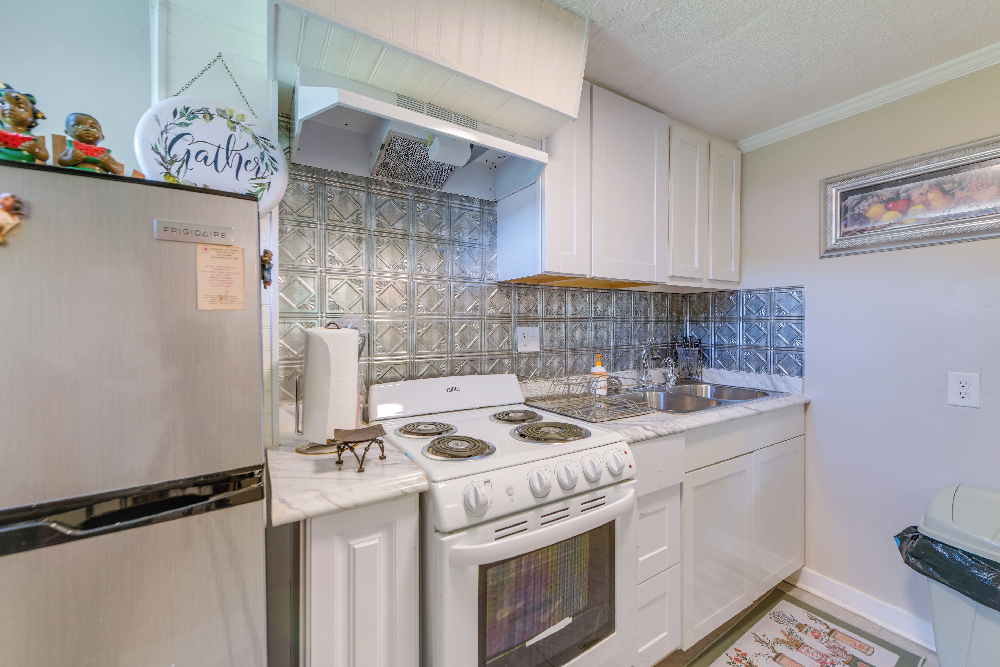 A kitchen with white cabinets, a white stove, and a patterned backsplash.