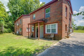 A two-story brick house with a covered front porch and a small attached garage. - Walk to Tuskegee University! Apt w/ Shared Yard (Tuskegee)