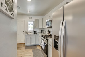 A modern kitchen with white cabinets, stainless steel appliances, and a window with a view.